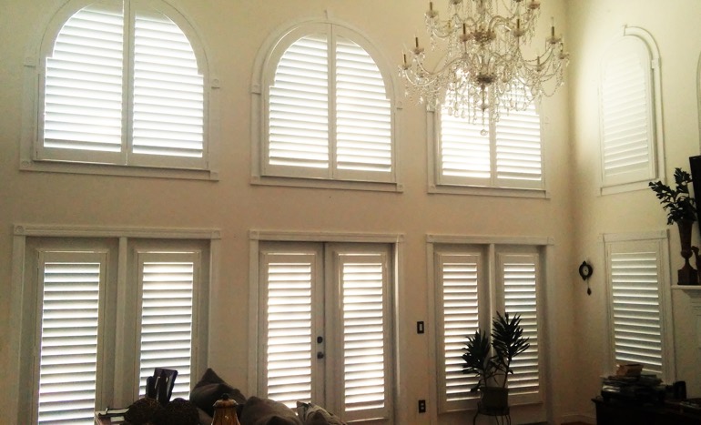 Great room in two-story Hartford house with plantation shutters on high windows.