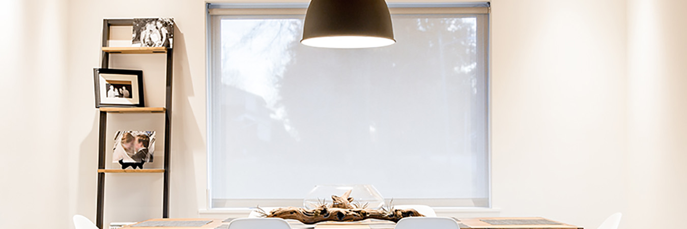 Modern beige dining room with a white window shade on a large window.