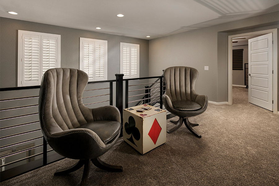 A white window treatment on a darker wall can do wonders for your Hartford home. two chairs and a small dice-themed table in front of a stairwell with shuttered covered small windows