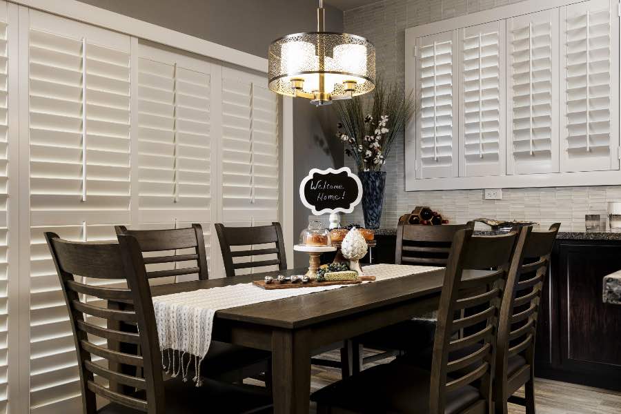 Sun in your eyes? A sliding door shutter effectively keeps light out of your living areas. White Polywood shutters on a sliding patio door in a dining room