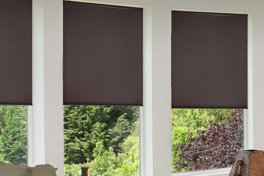 Cellular shades like these darker, blackout options have honeycomb-like cells that trap air to prevent thermal transfer. Dark cellular shades cover large windows in living room