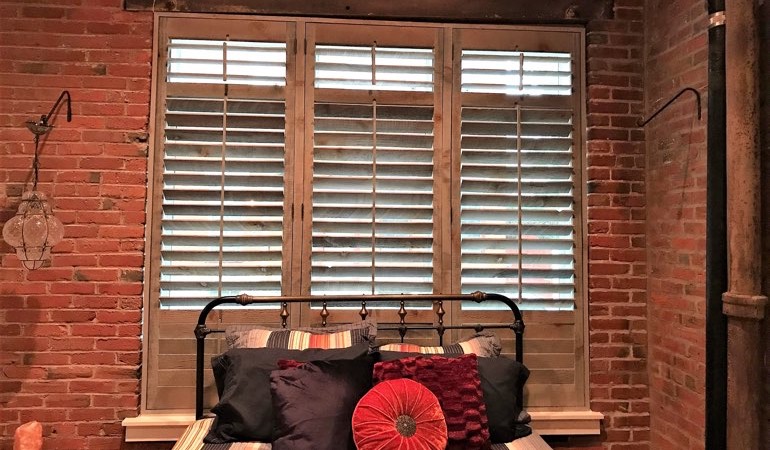 Reclaimed wood shutters provide an organic touch to your minimalist design. Reclaimed wood shutters next to brick wall.