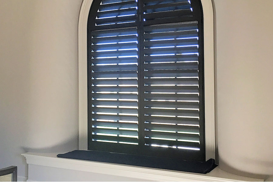 Interior shutters are suitable for any window, including this custom arched opening. Rich, dark interior shutter with arched top