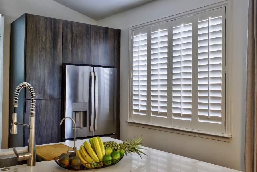 Homeowners use indoor window shutters in Hartford when they want attractive and functional window treatments. Polywood shutters on a large kitchen window