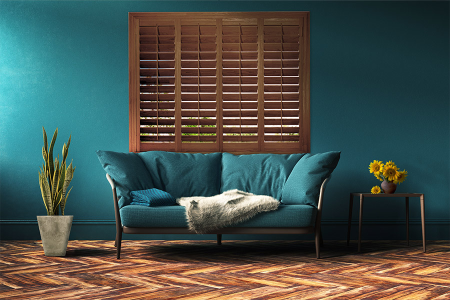 Stained wood Ovation shutters add a natural element to your living space. Ovation shutters above a leather couch