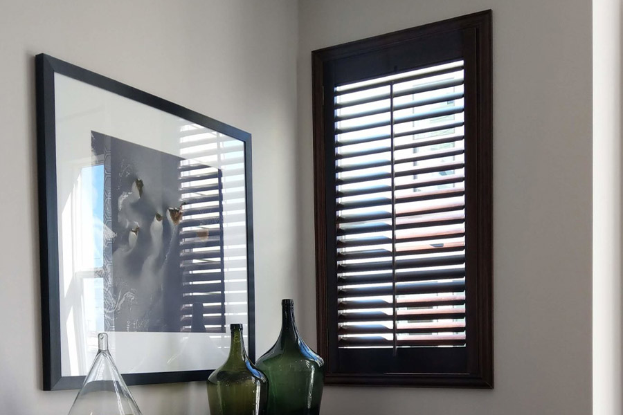 Onyx black painted wood shutters go well with any stylish decor for your home. Black painted wood shutters in a corner window area.