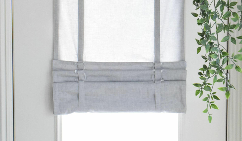 With a tiered tumble shade in Hartford, you can block sun glare all year round. Gray rolled tumble shade on a glass door