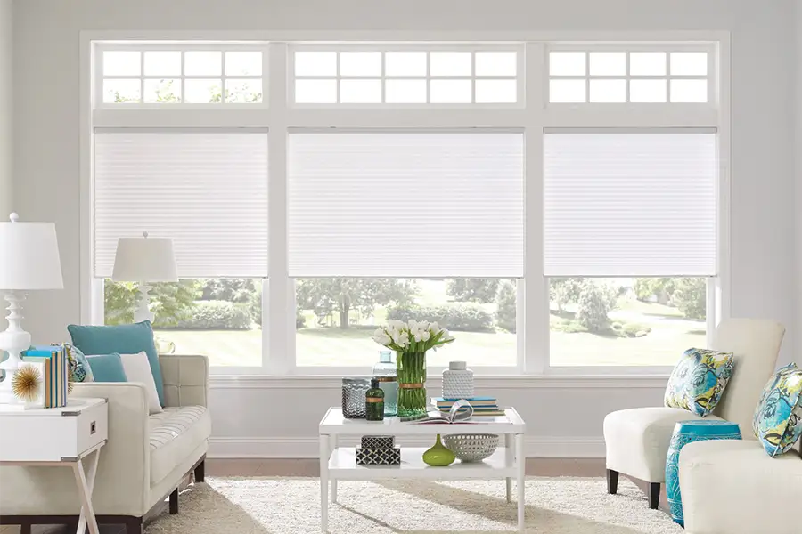 Insulating cellular shades can help keep cold air and hot UV rays from entering your Hartford home. White cellular shades on windows in a white living room