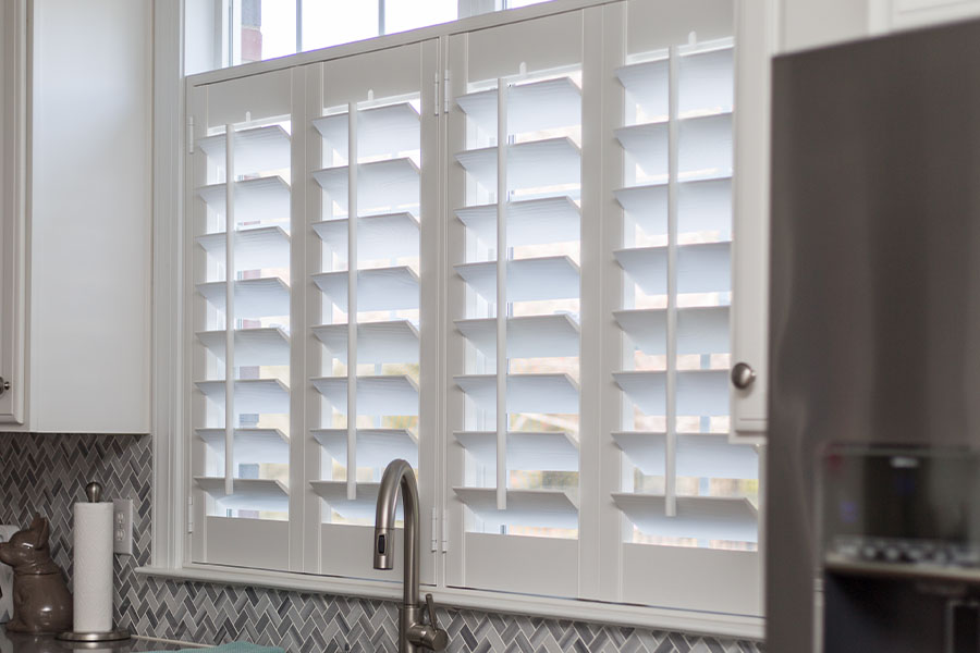 Choose Polywood shutters if you need a window treatment that can withstand adverse conditions like kitchen splashes and splatters. White Polywood shutters on a kitchen window