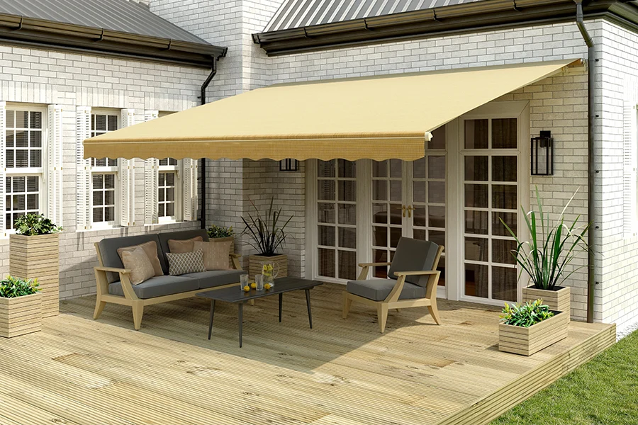 A beige retractable awning over a wood deck on the back of a white brick house